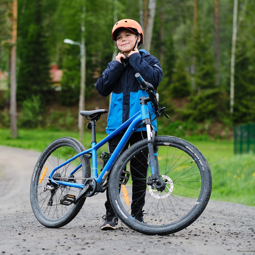 Iloinen poika polkupyörän takana.