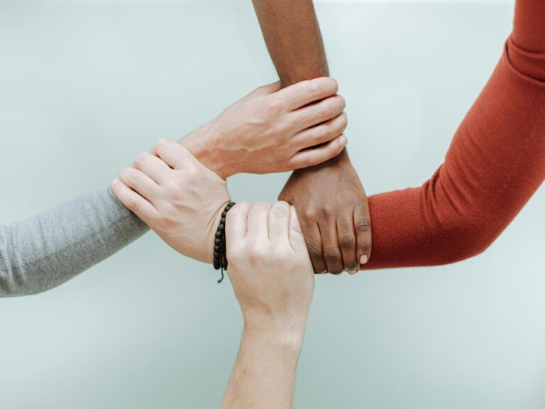 Neljä kättä pitää toisiaan ranteista kiinni.