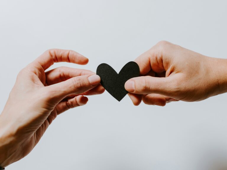 Kaksi kättä pitelee sydäntä.