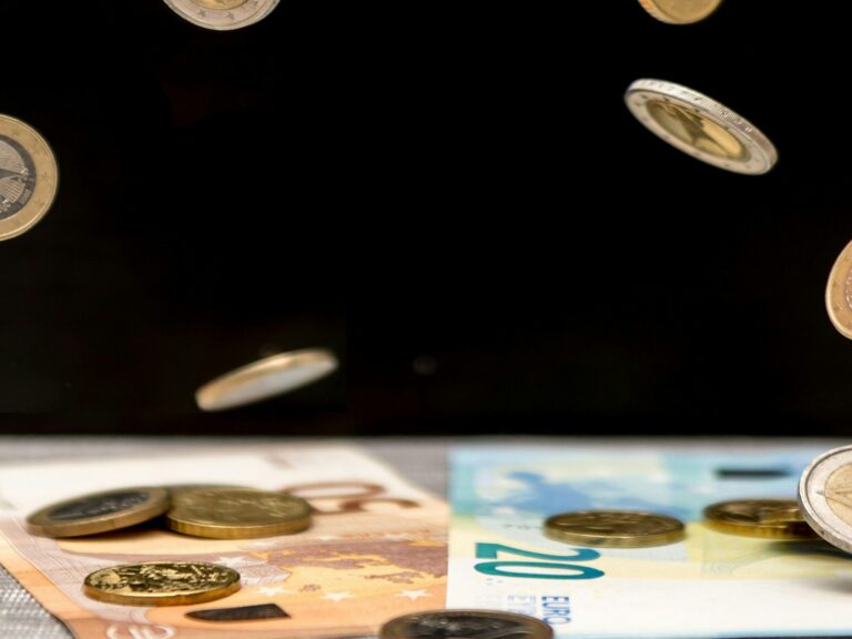 Eurokolikoita putoilee 20 ja 50 euron seteleiden päälle.