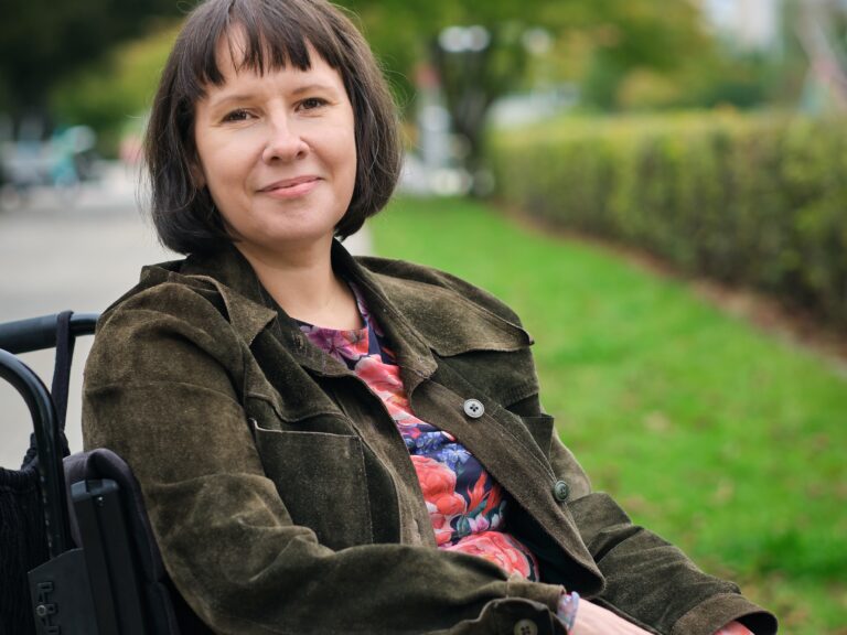 Päivi Montgomery kuvattuna ulkona pyörätuolissa.